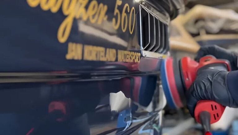 Blauwe romp van een boot die gepolijst wordt met een flexmachine, met een glanzende afwerking in het proces